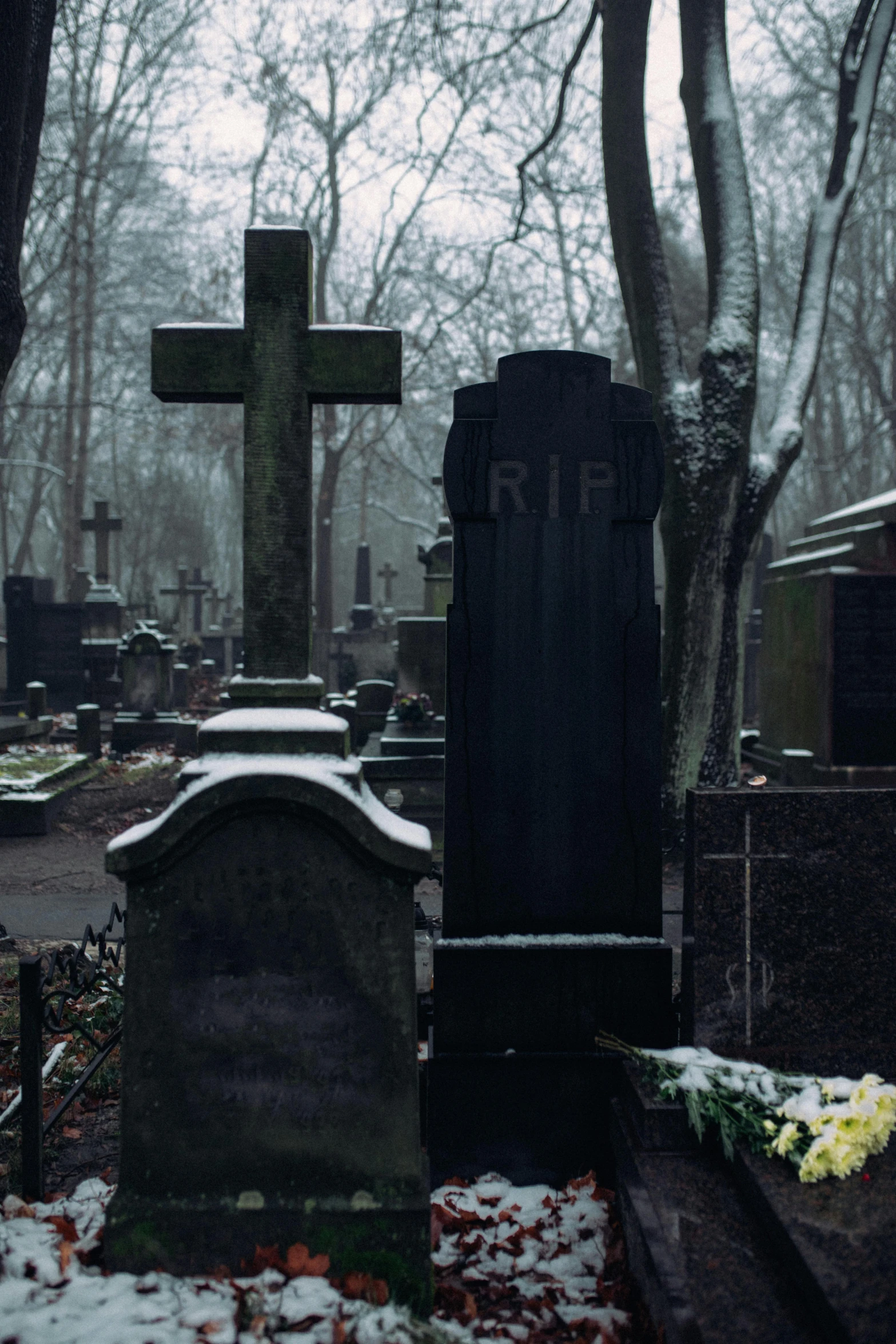 snow covered headstones and flowers in the churchyard