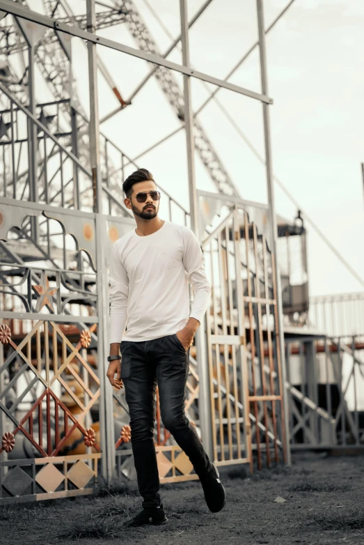 a man with black pants and boots walking next to a metal structure