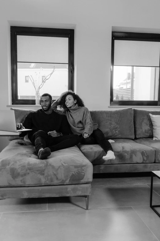 two people sitting on a sofa looking at soing on the floor