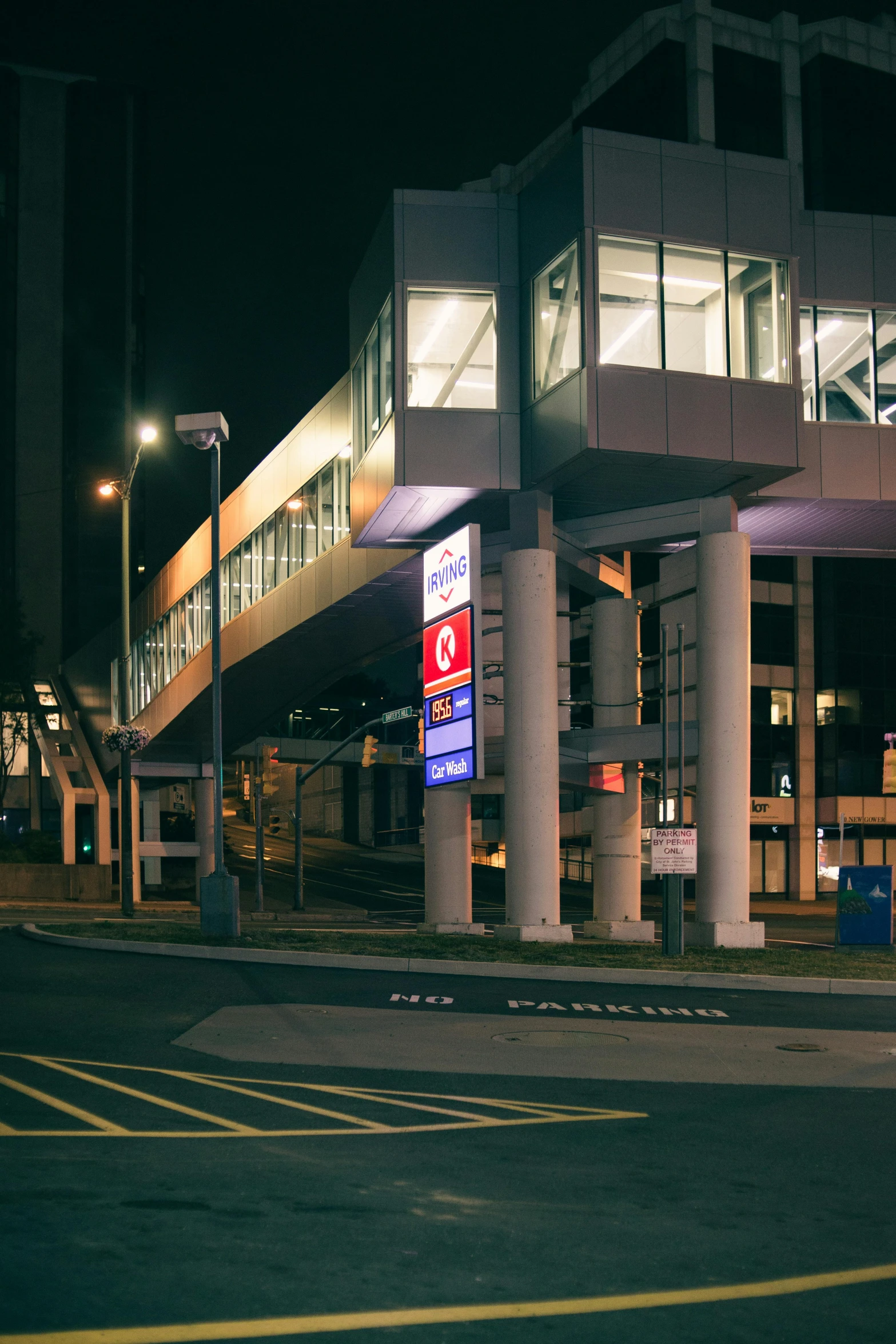 an empty street next to a building with lights and a stop sign in front