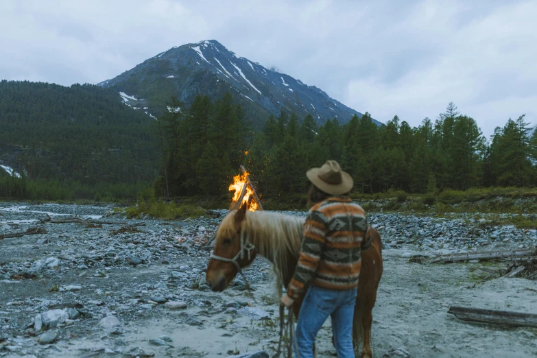 man with horse next to mountain and fire