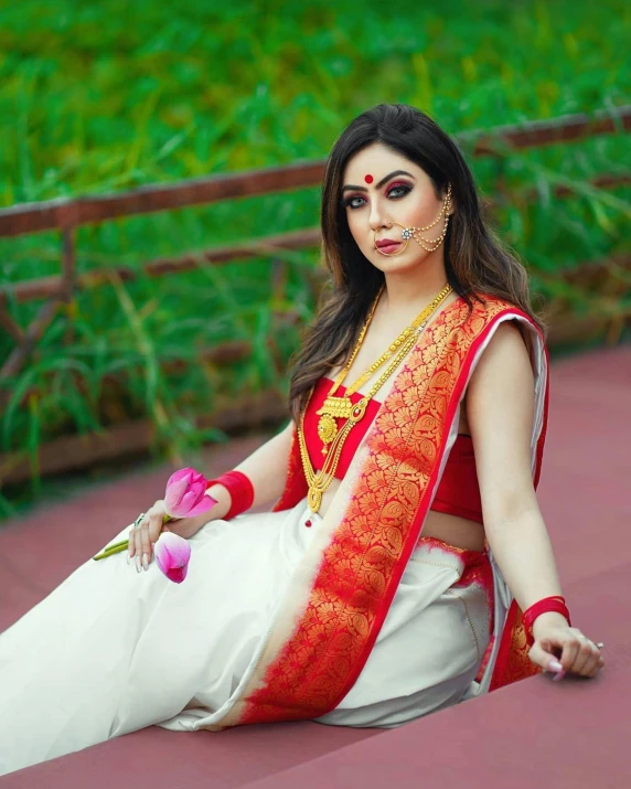 woman with a necklace on sitting down and wearing a white sari