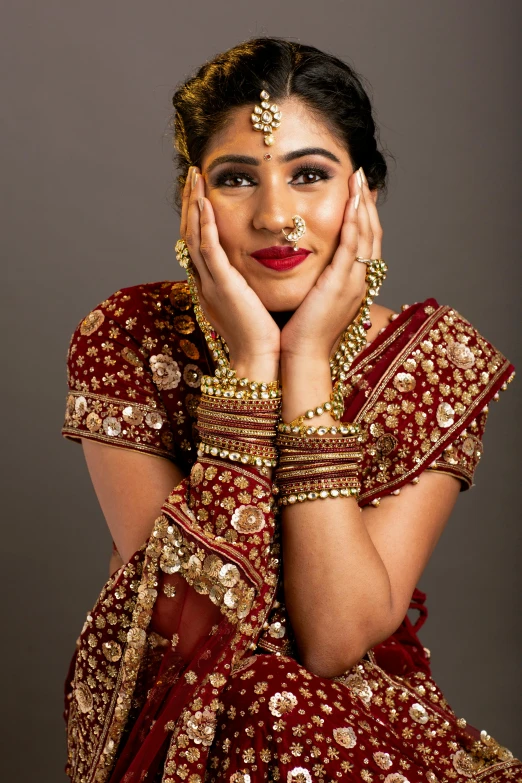 a woman in red and gold clothes with her hand under her chin