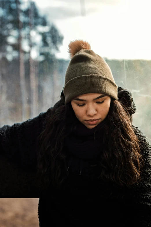 a girl with her hair in wind blown down, wearing a beanie