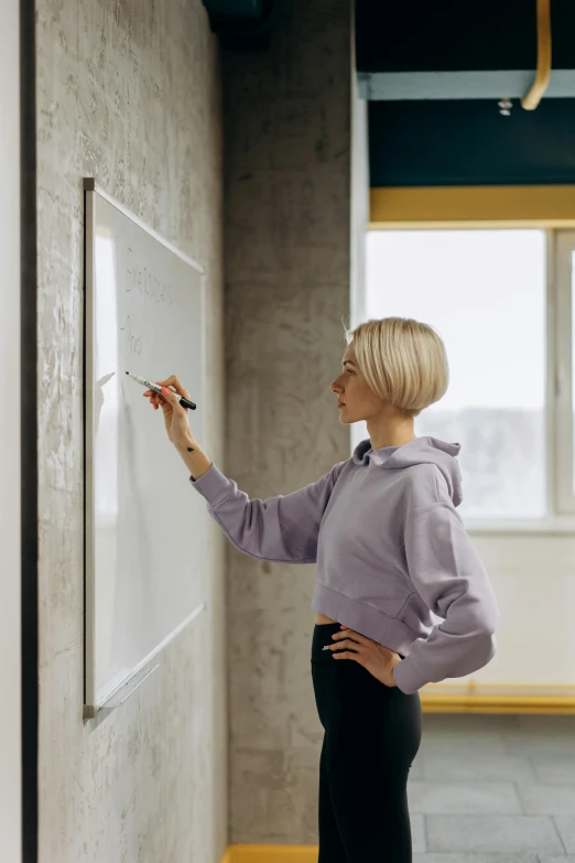 a woman is writing on a white board in an office