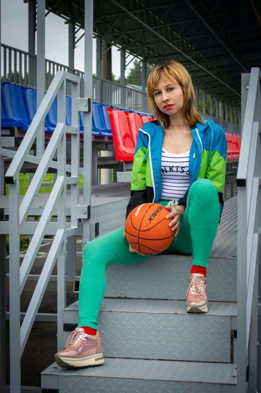 a beautiful young lady holding a basketball while sitting on some steps