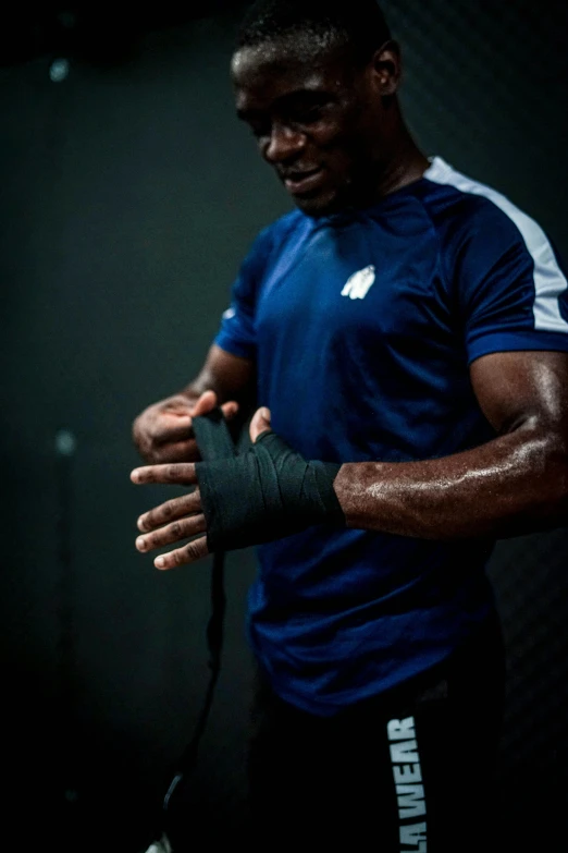 man using arm cast on black background in light room