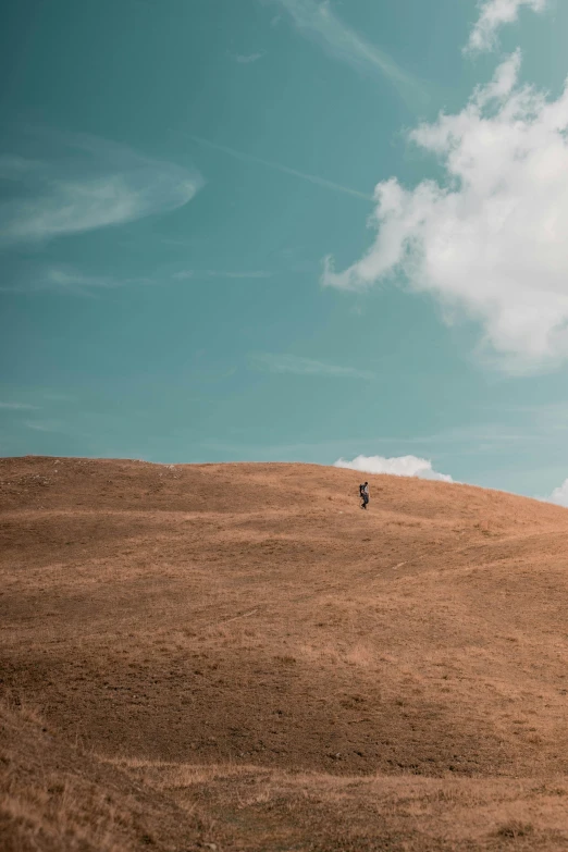 two people walking down a hilly hill with the sky in the background