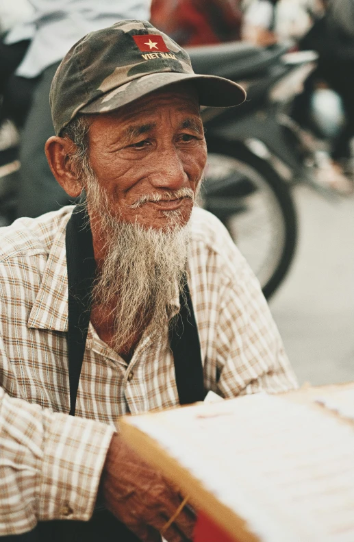 old man smiling for the camera wearing a plaid shirt