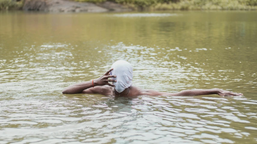 man in white shirt and shorts laying down in a lake