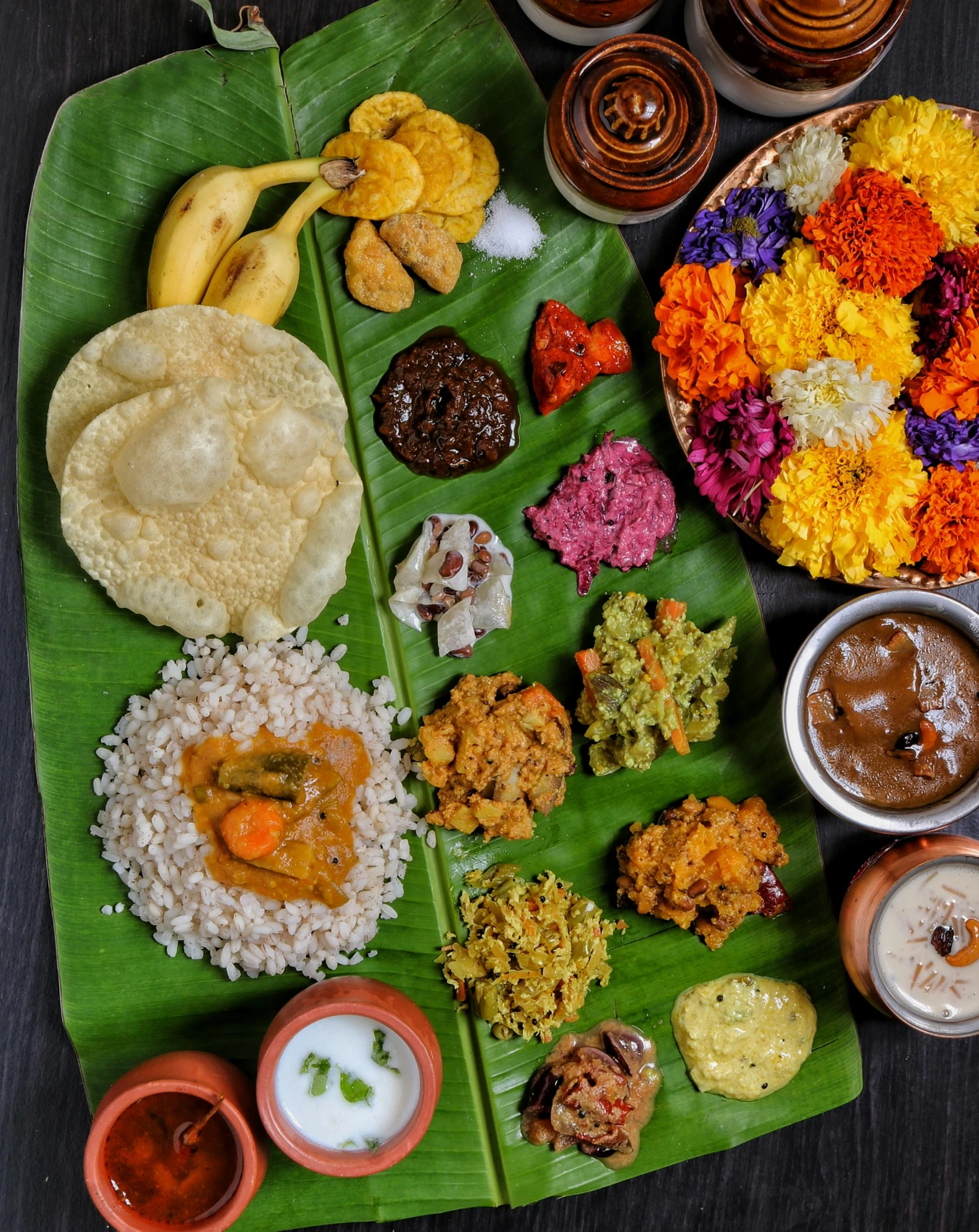 a long banana leaf with plates of food on it