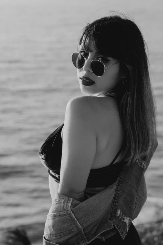 black and white pograph of a woman wearing sunglasses and holding onto a jacket