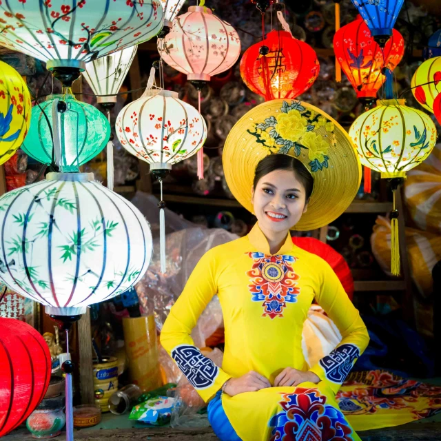 a woman sitting next to a table full of paper lanterns