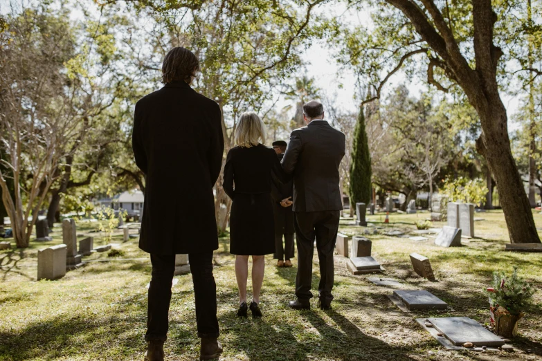 two men and one woman are visiting the cemetery