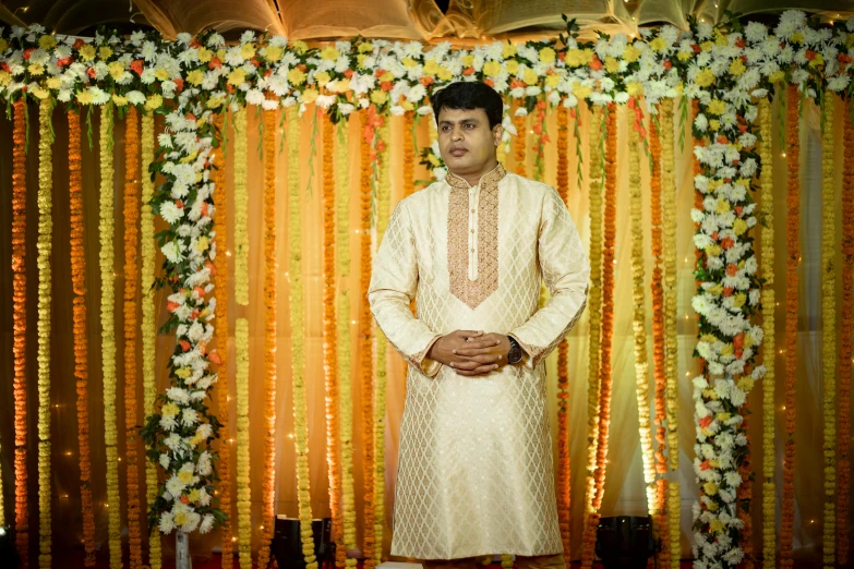 a man in white is standing in front of a yellow and orange backdrop