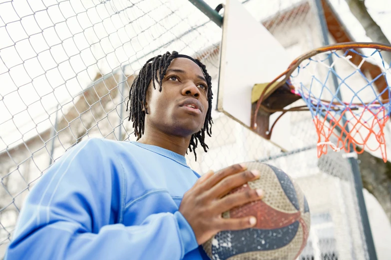 a man with dreads standing in front of a basketball hoop