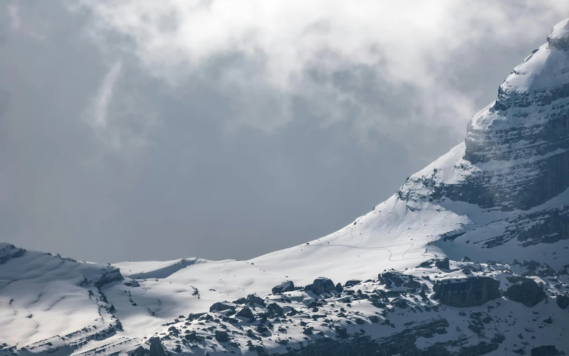 the sun is shining through the clouds over a snowy mountain