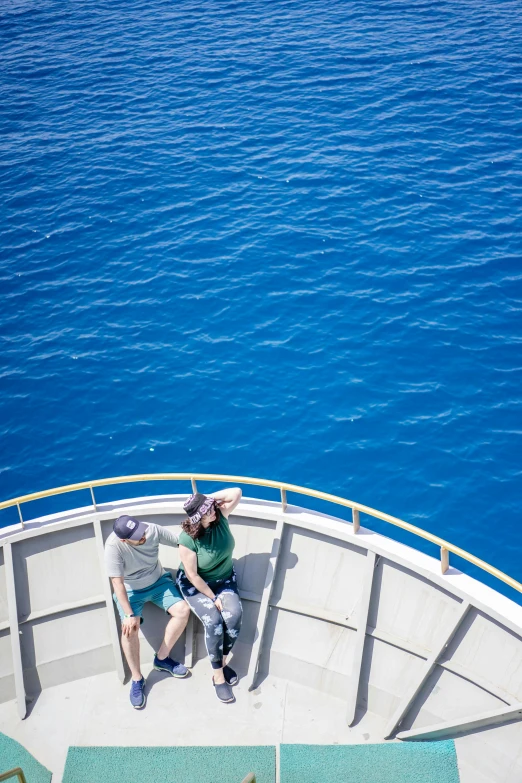 a couple on the back of a boat in a bright blue sea