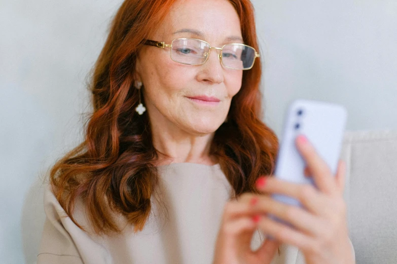 a woman with red hair wearing glasses looking at a cell phone