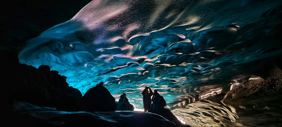 two people stand inside of an ice cave