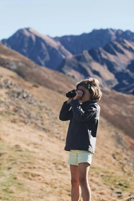 the girl is standing on the side of the mountain while talking on a phone