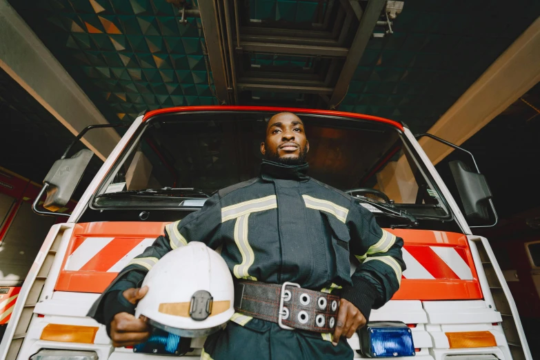 a man dressed as a fireman and standing next to his truck holding a helmet