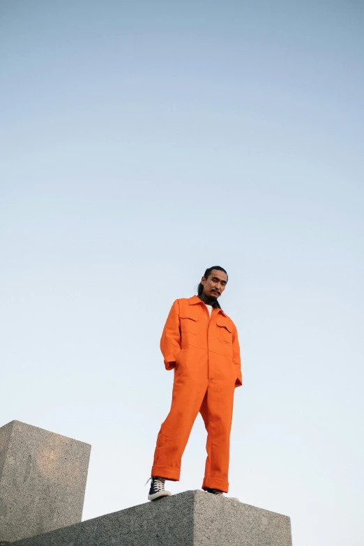 a man wearing an orange jumpsuit is standing on concrete blocks