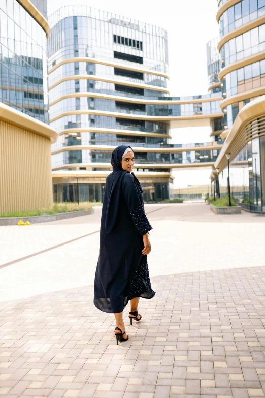 woman with black hijab walking down sidewalk in front of buildings