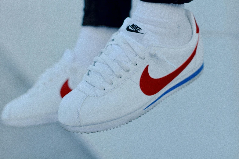 close up of a man's white shoes with red and blue accents