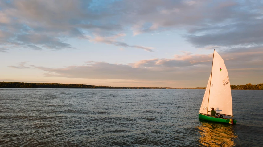 a sail boat with a person on it sitting in the water