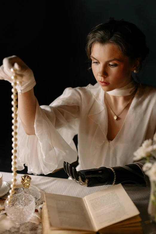 a woman wearing gloves holding a rosary at a table