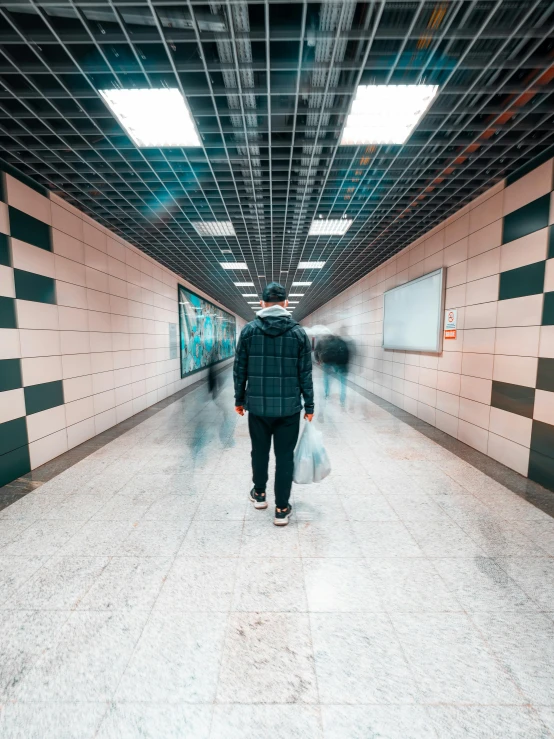 a man in an empty subway station with a white bag