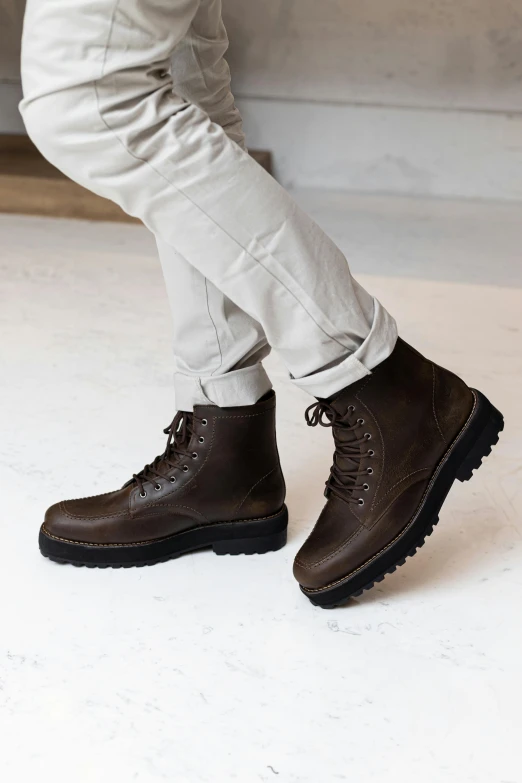 a person is standing on the floor in a pair of dark brown boots