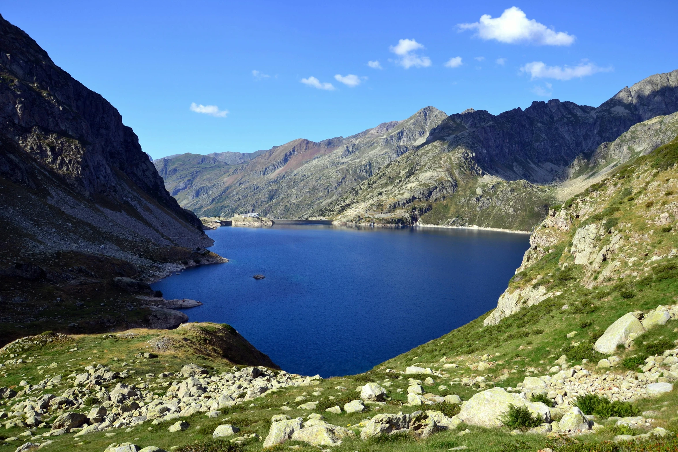 a large blue lake near some mountains on a sunny day