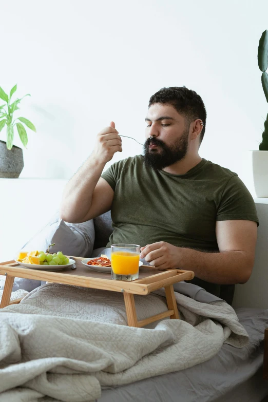 a man sitting on a bed and eating cereal from a tray