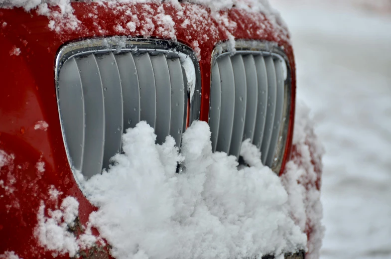 the front of a red car is covered with snow