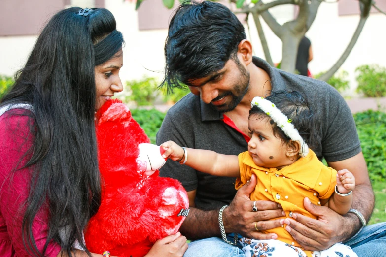 two adults and one child sitting outside with a heart shaped pillow