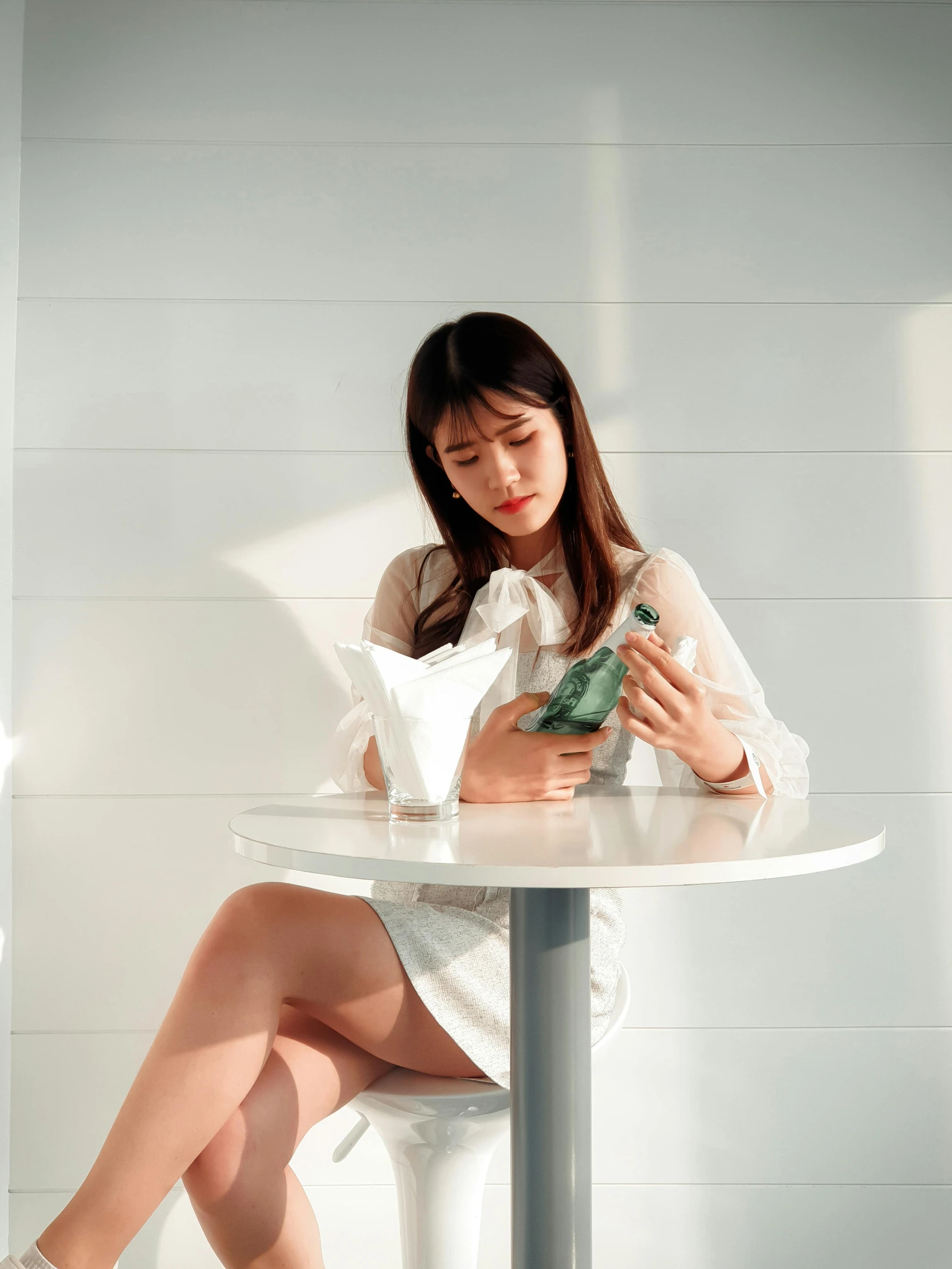 woman in white dress sitting on stool with bird