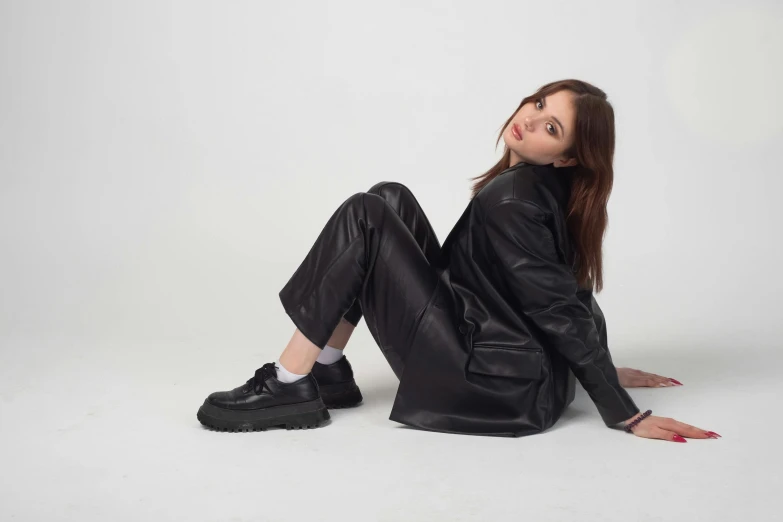 woman in a leather jacket and boots sitting on the ground