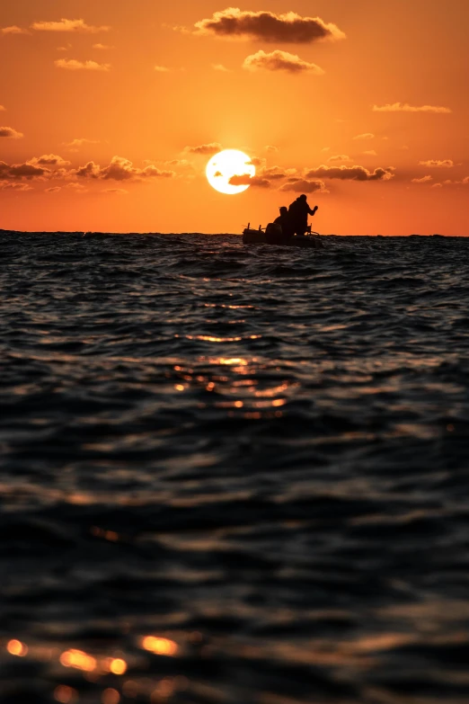 a couple of boats sailing across a body of water at sunset