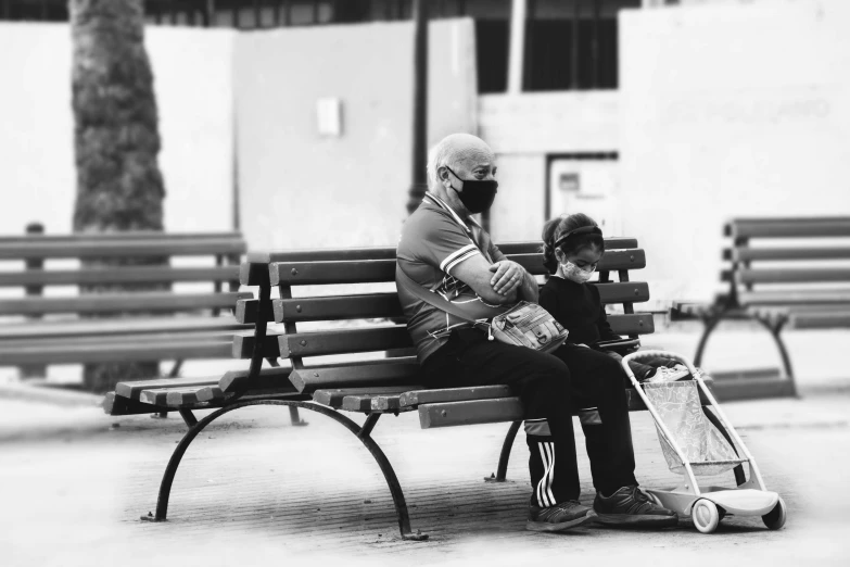 an old man and young child sitting on a park bench