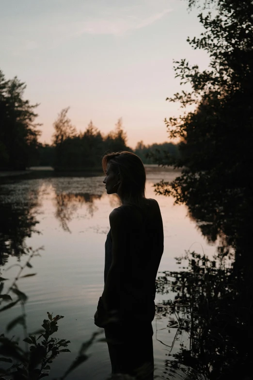 the woman is standing by a body of water