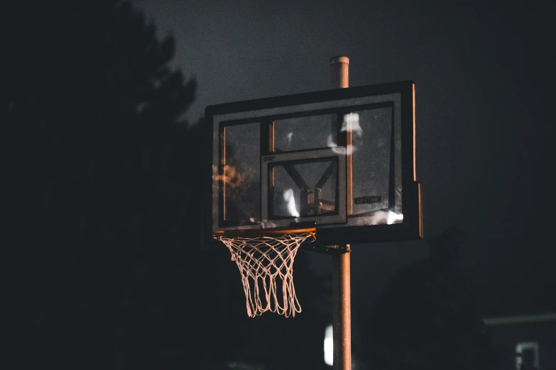 a basketball goal with white boks flying from it at night