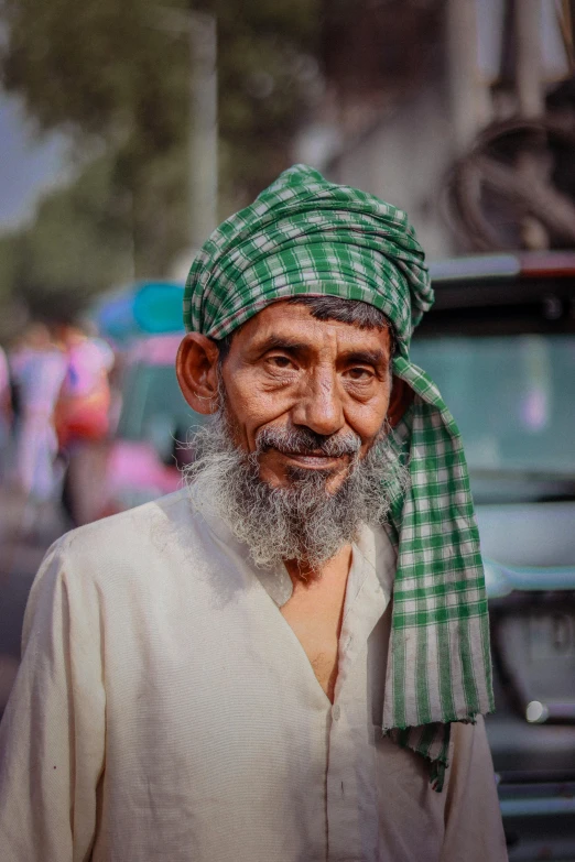 a man is standing in front of a truck wearing a green and white turban