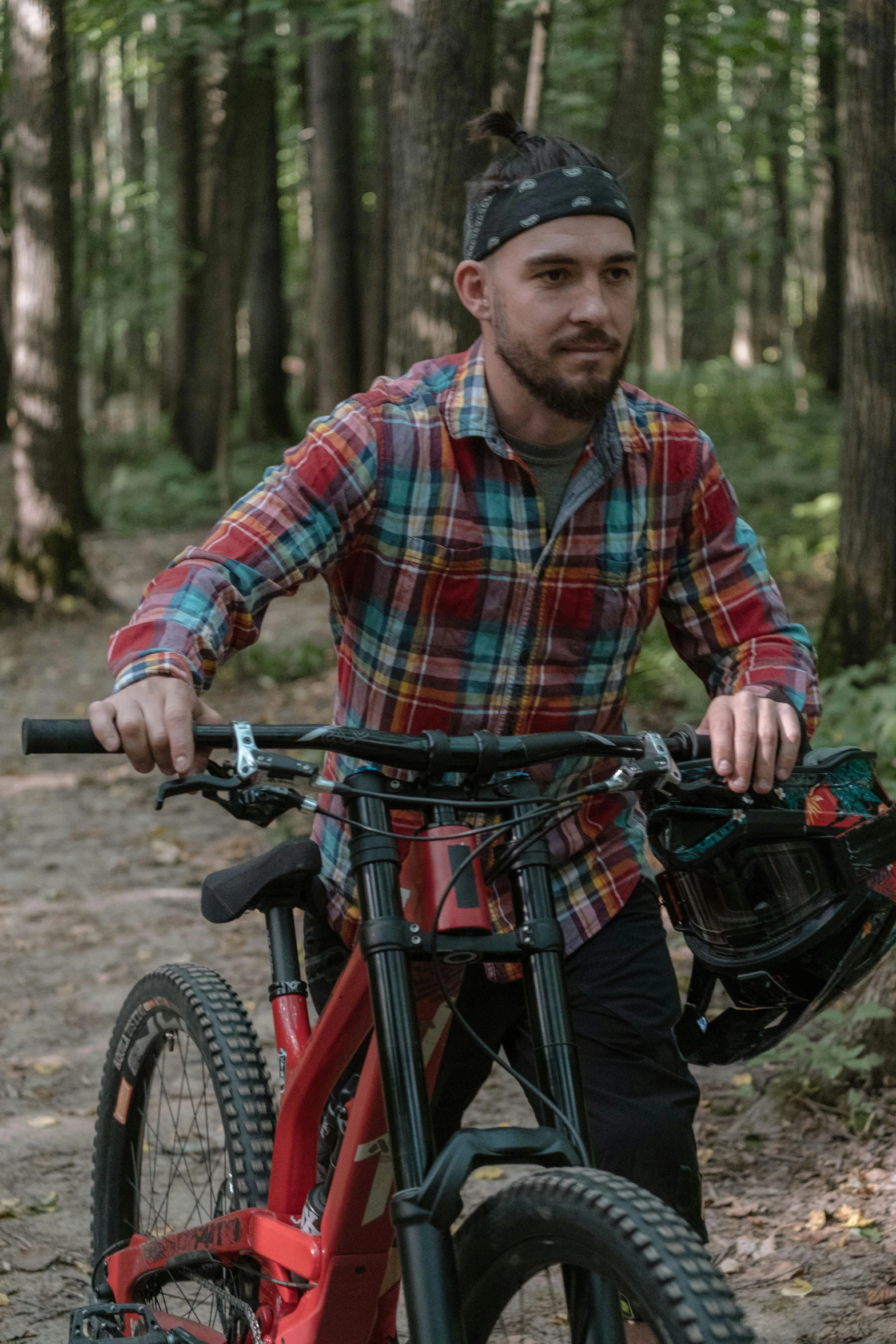 man with bike sitting in wooded area with trees in background