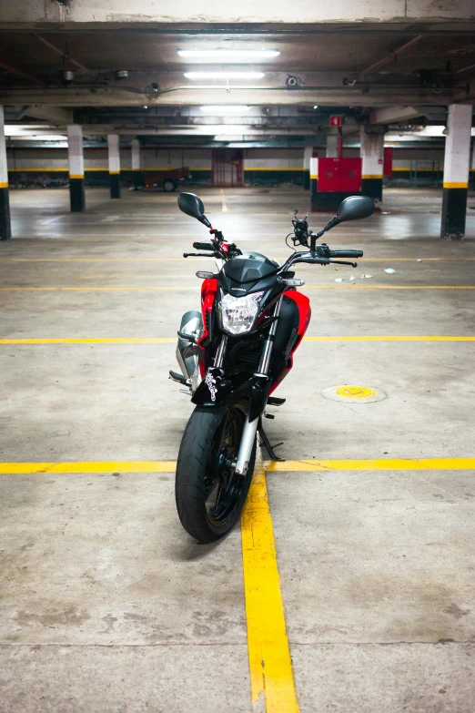 a red motorcycle parked inside of a parking garage