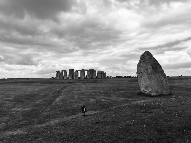 a black and white pograph of a field with some grass and an over sized rock