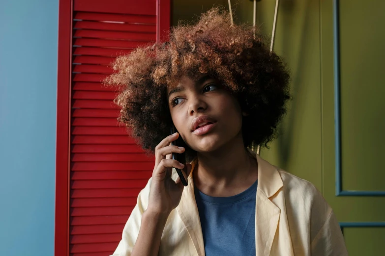 a young woman with short red curly hair talking on a cellphone