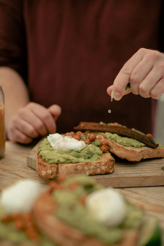 the man is making a sandwich that contains guacamole