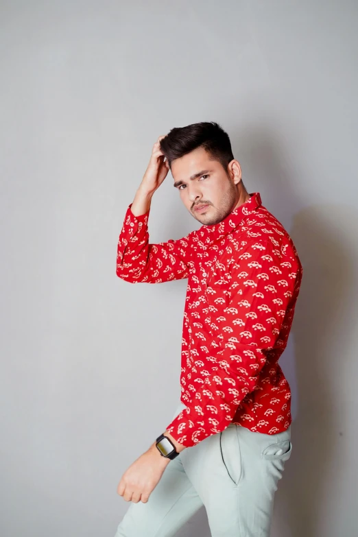 a young man wearing a red shirt and grey pants